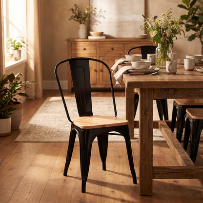 Silla Tolix negra con asiento de madera junto a una mesa de madera maciza